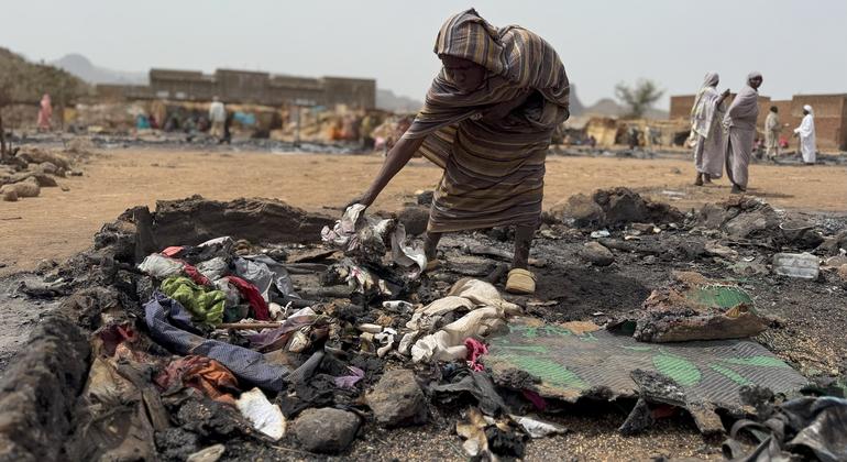 A woman searches through the burnt remains of her shelter at a displacement camp in Darfur, Sudan.